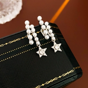 Detail of star pendant earrings with pearls and pavé zircons on a black jewelry box