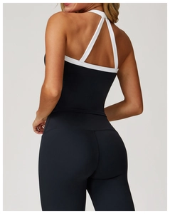 Détail des bretelles croisées blanches sur haut de yoga noir offrant contraste et maintien