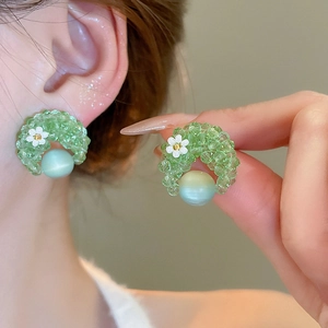 Close-up of green beaded flower earrings featuring a white daisy and light teal gemstone
