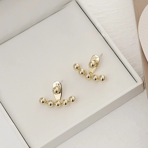 Detail of gold beaded curved earrings placed in a premium white jewelry gift box