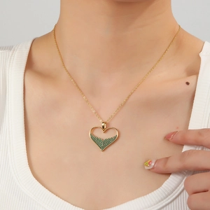 Elegant 18K gold heart necklace featuring micro-set green emerald stones on a female model