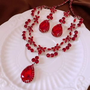 Vue détaillée d'une parure collier et boucles d'oreilles aux gouttes de zircon rouge