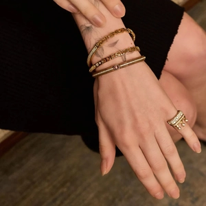 Gros plan d'une bague couronne dorée sertie de zircons et de bracelets superposés