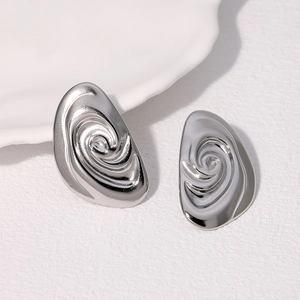 Macro shot of silver vortex spiral stud earrings on a textured light background