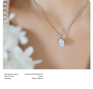 Close-up of titanium steel oval pendant with leaf engraving worn by a model