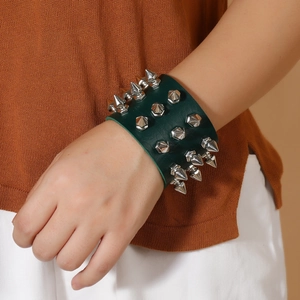 Punk style dark green leather wristband with three rows of silver metal spikes on a model