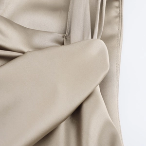 Robe élégante en satin beige avec manches courtes nouées et texture soyeuse