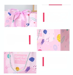 Detail of pink gift bag with starry sky prints, silk ribbon bow, and sturdy silver handles