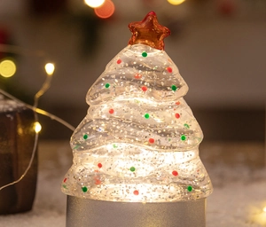 Close-up of glowing desktop Christmas tree lamp with colorful dots and star topper