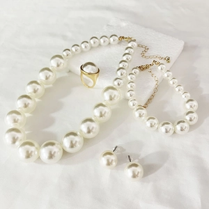 Elegant pearl jewelry set featuring necklace, bracelet, ring, and earrings on white marble
