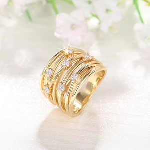 Primer plano de anillo dorado multicapa con circonitas sobre un fondo floral blanco