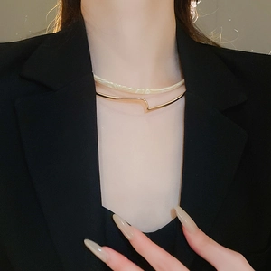 Detail of a double-layer resin and gold collar necklace worn on a black blazer
