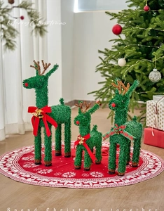 Detailed view of green tinsel Christmas reindeer set with red bows and festive bells