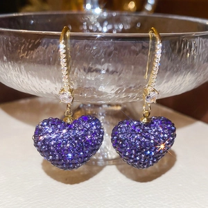 Detailed macro view of vintage gold earrings with heart-shaped purple zircon and fine pavé