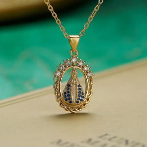 Gold plated Virgin Mary pendant necklace with blue zircon and pearls on a book background