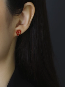 Close-up of model wearing red melting smiley face enamel earrings in 925 silver