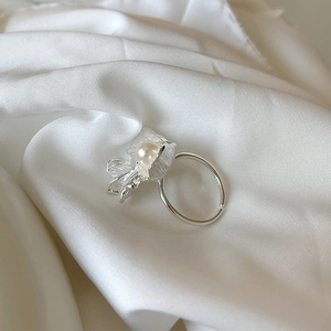 Detail of 925 silver flower ring with freshwater pearl on white silk background