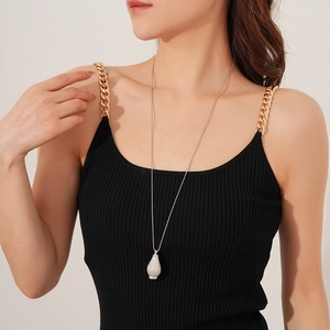 Close-up of a silver textured teardrop pendant on a long bead chain necklace worn by model