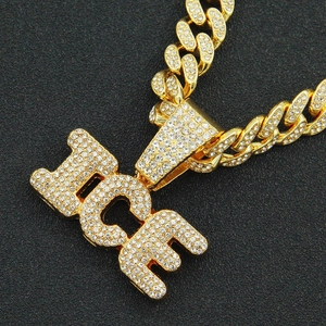 Close-up of sparkling gold iced-out ICE letter pendant on a Cuban link chain necklace