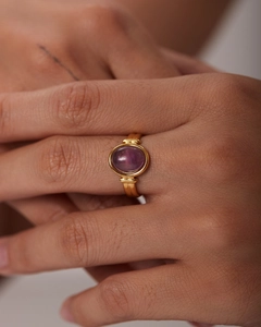 Dettaglio di un anello vintage in oro 18K con gemma viola ovale indossato sulla mano