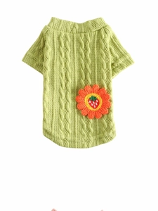 Close-up of green cable knit dog sweater with vibrant orange and red crochet flower detail
