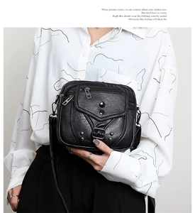 Détail d'un sac bandoulière en cuir souple noir avec rivets et plusieurs poches zippées