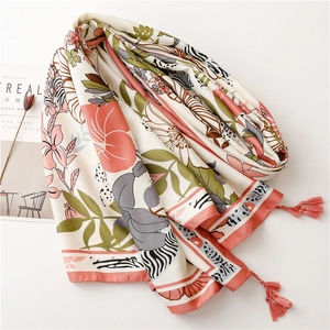 Detail of floral print scarf with soft orange tassels beside a minimalist magazine
