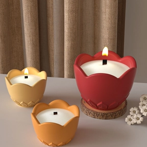 Embossed flower resin candle jars in red yellow and orange with wooden wicks on a table
