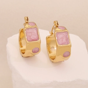 Irregular geometric gold earrings with pink marble resin inlays on a stone base