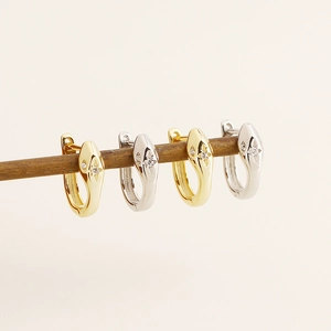 Detail of four snake-shaped stud earrings in gold and silver finish with sparkling stones