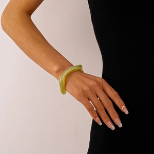 Macro detail of irregular green acrylic resin bangle showing hazy texture and glossy finish