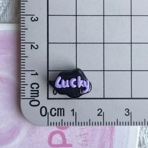 Macro shot of black resin Lucky charm next to a ruler for DIY craft sizing