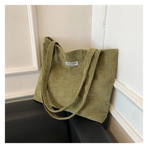 Close-up of green corduroy tote bag texture with minimalist white Fashion label
