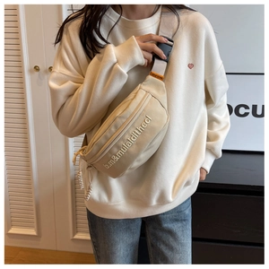 Detail of adjustable strap and buckle on beige canvas crossbody bag for women