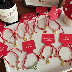 Detailed view of woven red strings with golden zodiac charms and gemstone beads