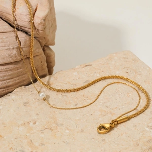 Elegant double-layered gold anklet with shell pearl and rope chain on stone background