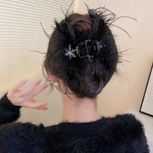 Détail de la pince à cheveux en plumes d'autruche noires avec flocon en strass brillant