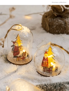 Close-up of lighted glass Christmas ornament with wooden reindeer and warm LED glow