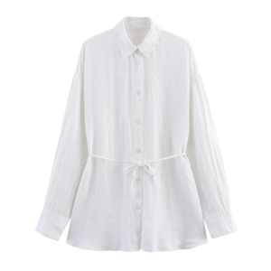 Detail shot of white linen shirt showing textured fabric, waist tie and button-up front