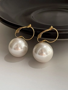 Detail of 14K gold plated earrings with glossy white resin pearl drops on black plate