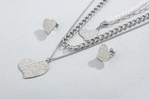 Detail of silver layered necklace and heart earrings set with hammered texture and pearls
