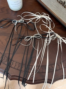 Detailed set of black and white bow hairpins with silver beaded fringe on wood
