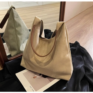 Detail view of khaki faux suede tote bag with brown strap on a stylish mirror background