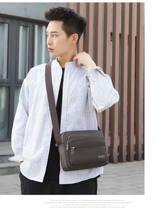 Detail of a brown leather messenger bag for men with multiple zipper pockets and logo