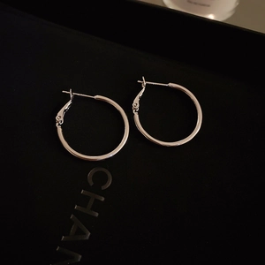 Macro shot of silver geometric hoop earrings on a textured black jewelry display box