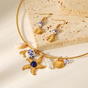 Detail of nautical ocean charms with porcelain beads on a gold stainless steel necklace