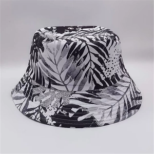 Detail of reversible bucket hat featuring black and white tropical leaf print texture