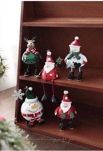 Close-up of five painted metal Christmas figurines on a wooden shelf for holiday decor