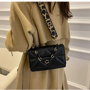 Detail of black quilted leather crossbody bag with chunky chain and wide pattern strap