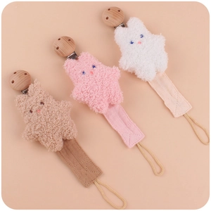 Three plush star baby pacifier clips in beige, pink, and white with wooden clips